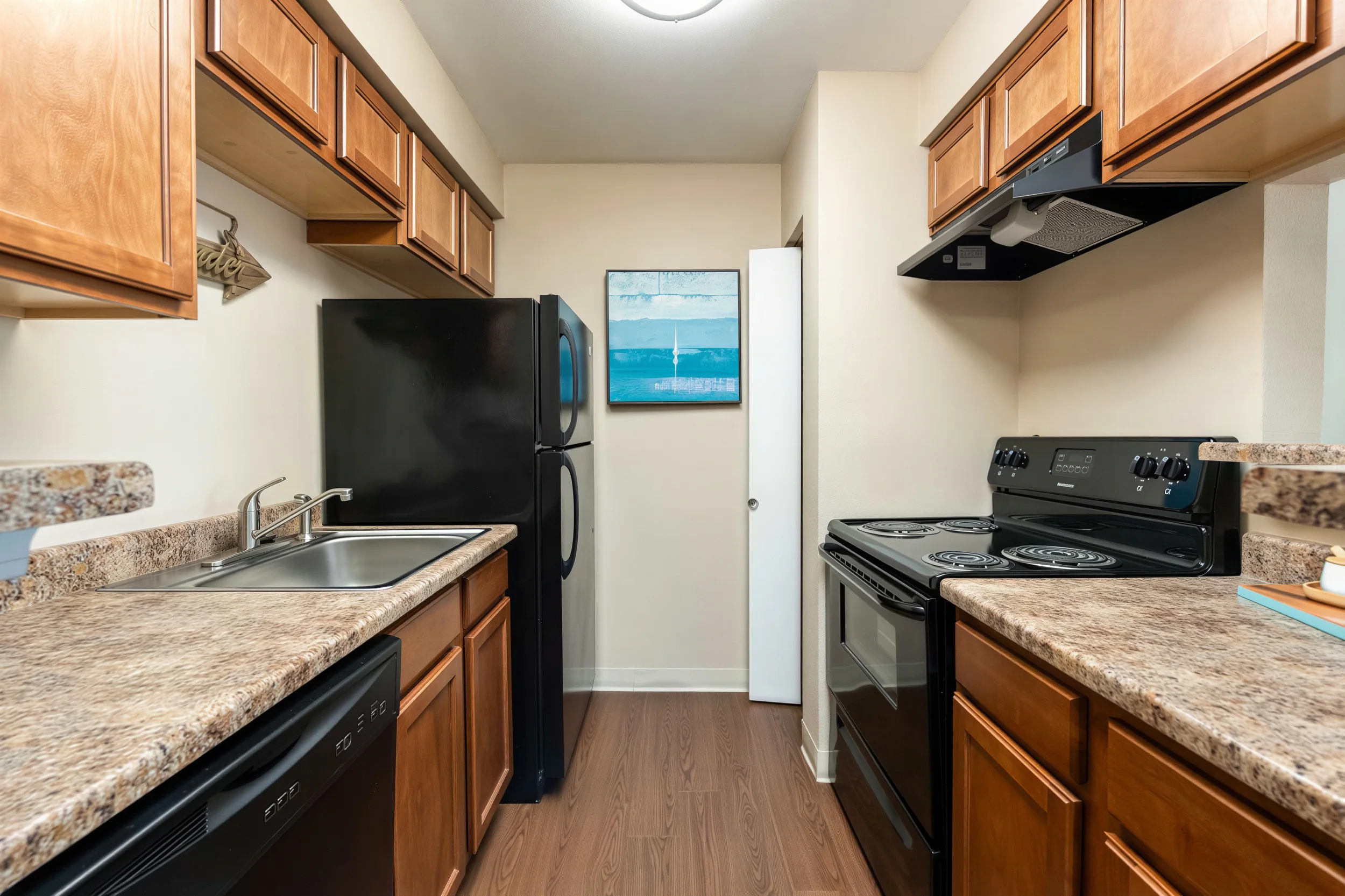 Apartment kitchen with wood cabinetry, full appliances, and ample counter space in Aurora, CO