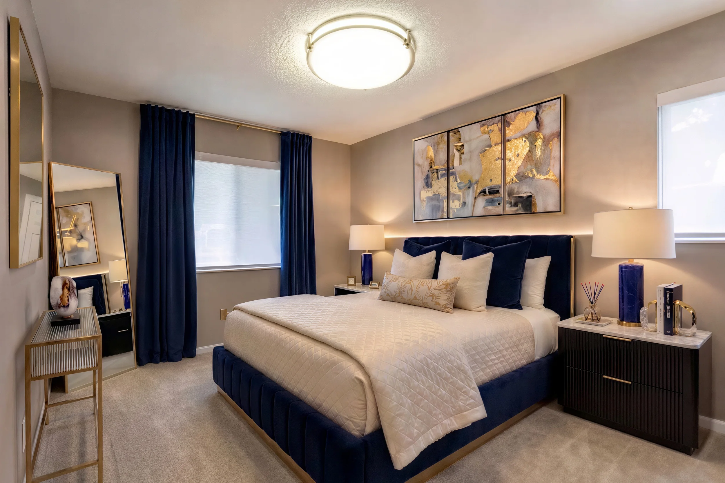 Spacious furnished bedroom with blue upholstered bed and modern artwork at Cambrian Apartments
